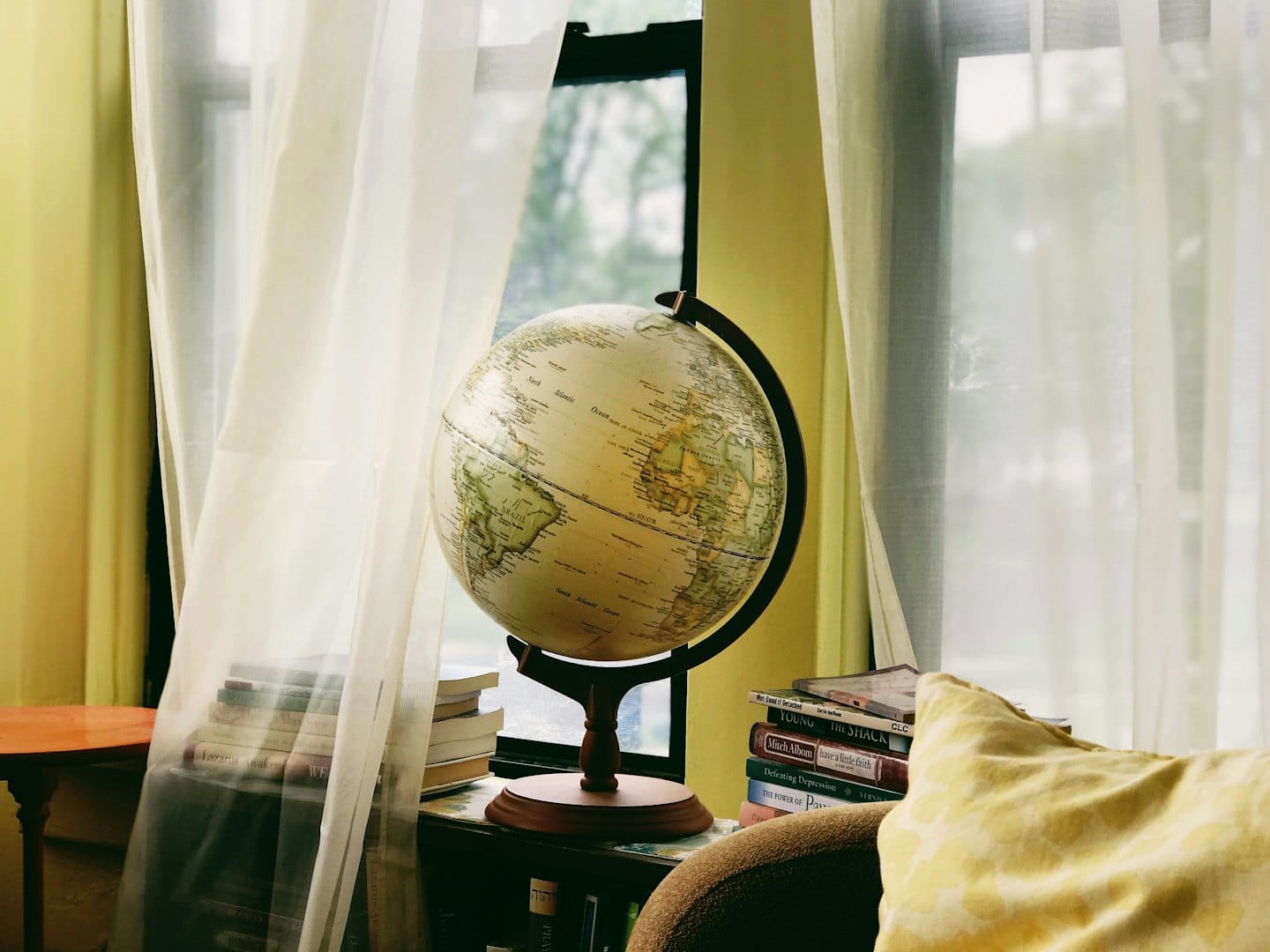 Globo antico su un supporto circondato da pile di libri.