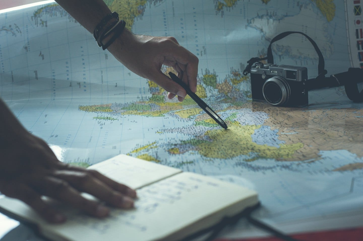 Mani che pianificano un viaggio con una penna su un mappamondo.