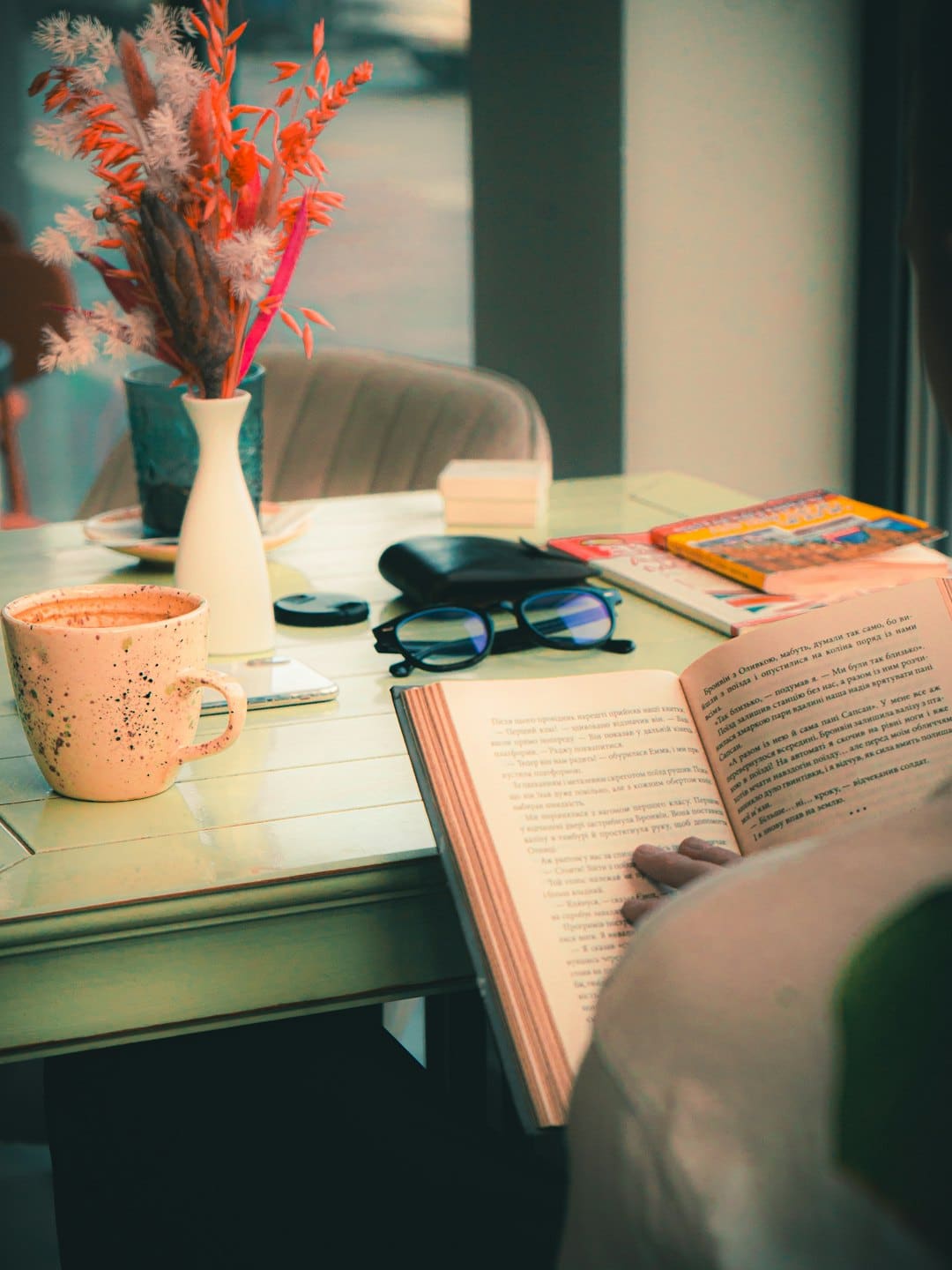 Una persona legge un libro a un tavolino di un bar.